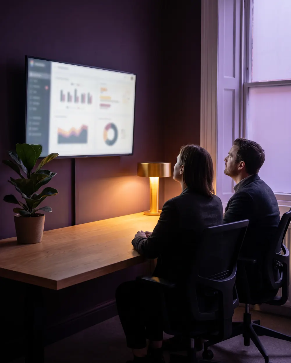 Illustrative image: two team members reviewing metrics on a large screen